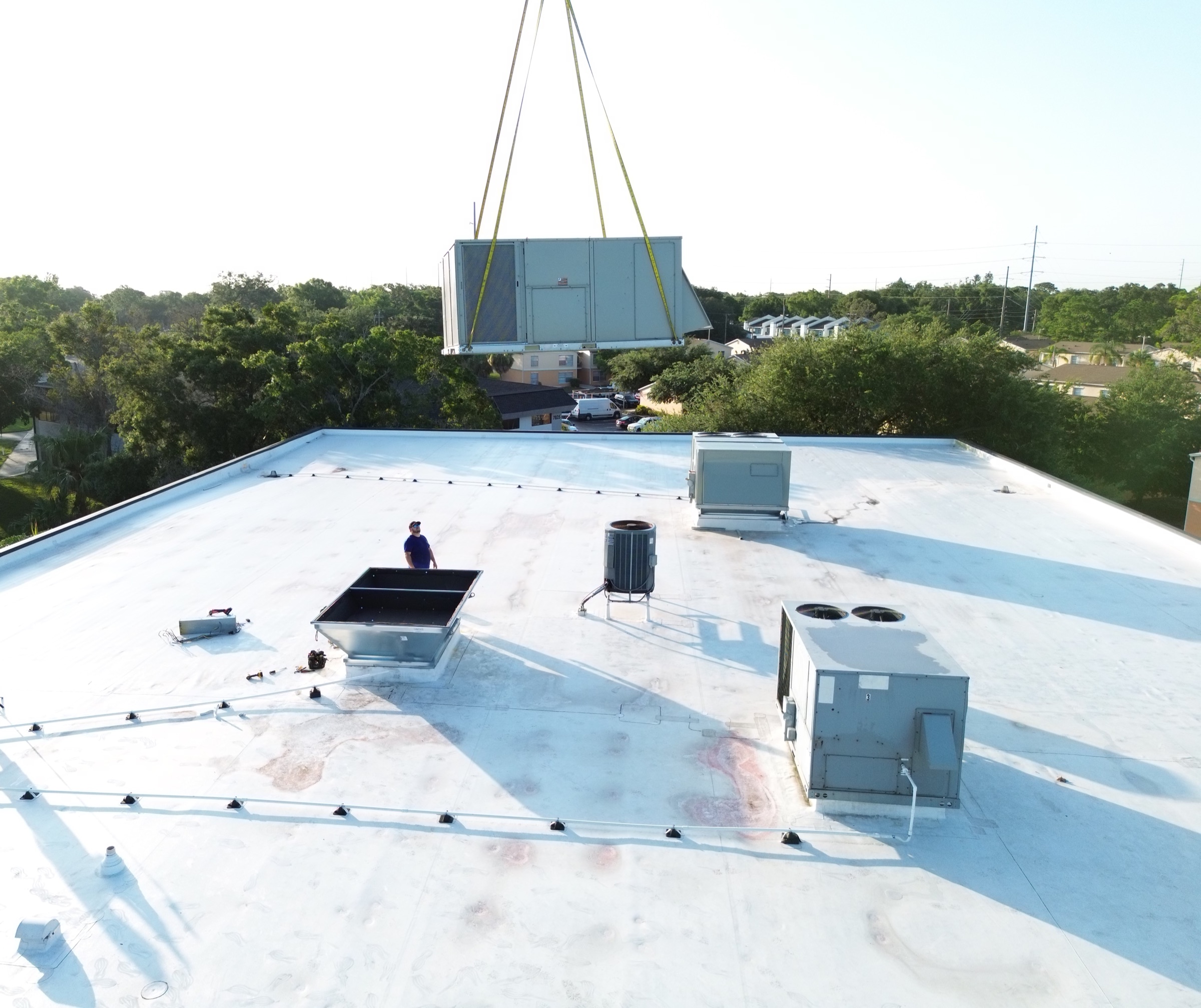 Crane lifting a commercial rooftop HVAC unit into place